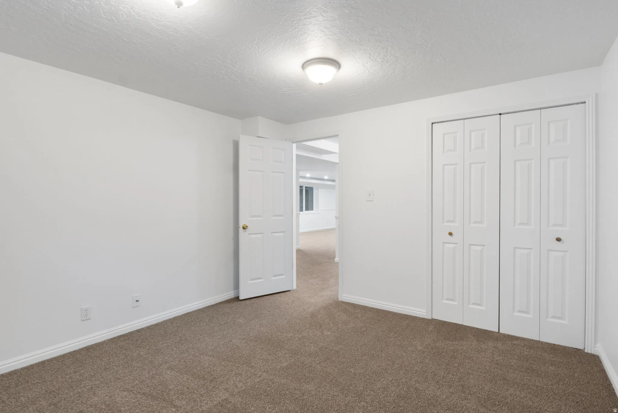 Neutral tone interior featuring carpet flooring, white walls, and bright overhead lighting