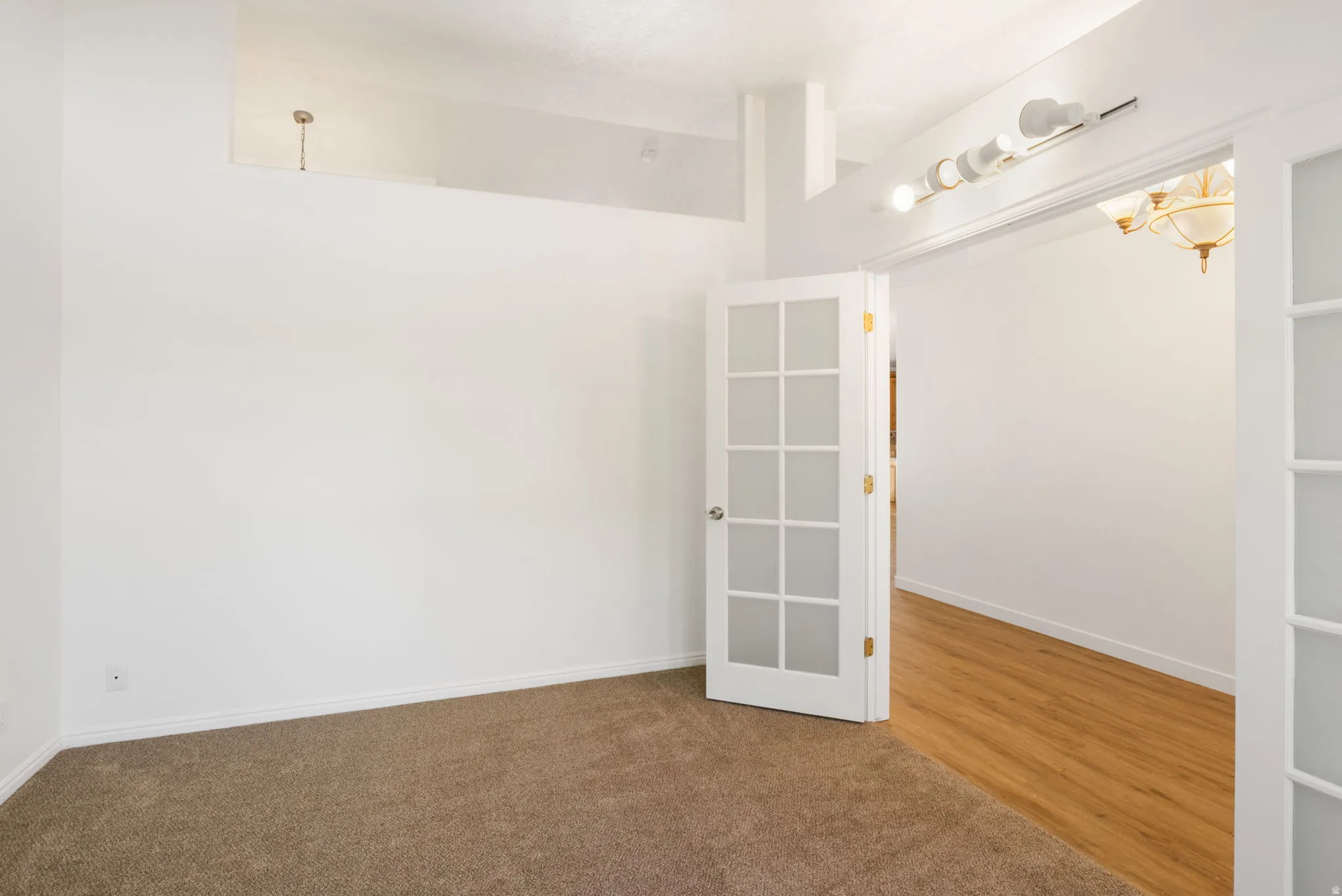 Carpeted room with white walls, baseboards, and a high ceiling