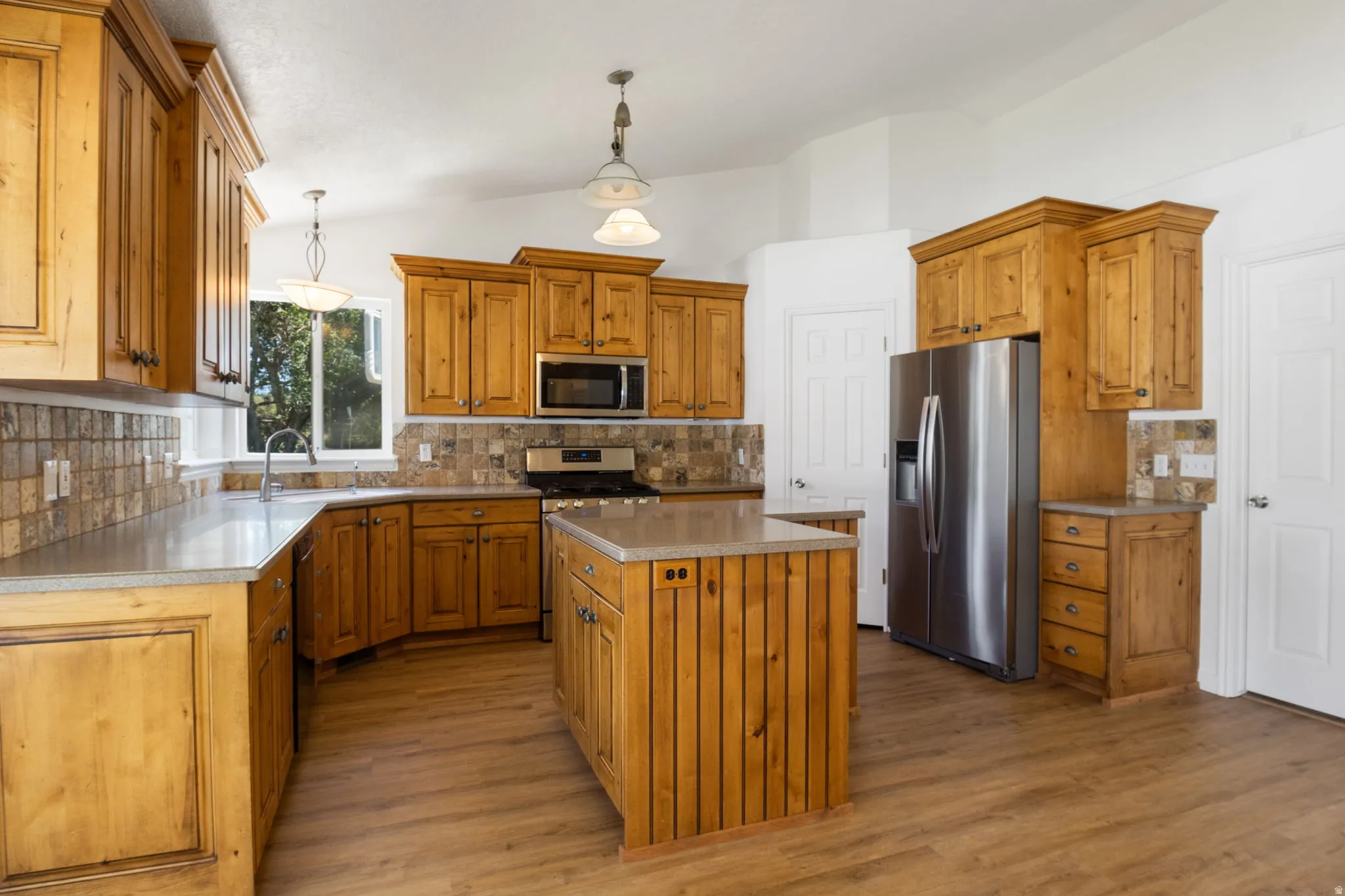 Kitchen featuring wood cabinetry, stone-look countertops, and plank-style flooring