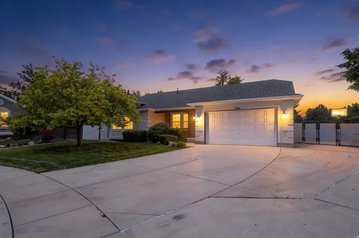 Exterior featuring a wide concrete driveway, an attached two-car garage, and a mature front yard tree