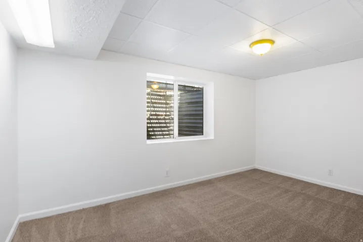 Neutral color palette room featuring a window with blinds, recessed lighting, a ceiling-mounted light fixture, and carpet flooring