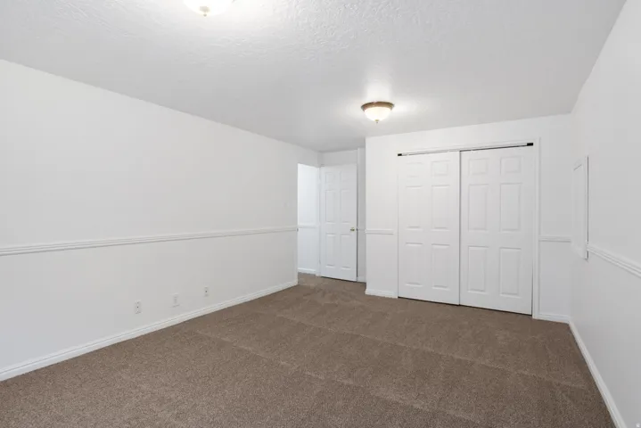 Spacious room featuring neutral carpeting, white walls, and a chair rail molding