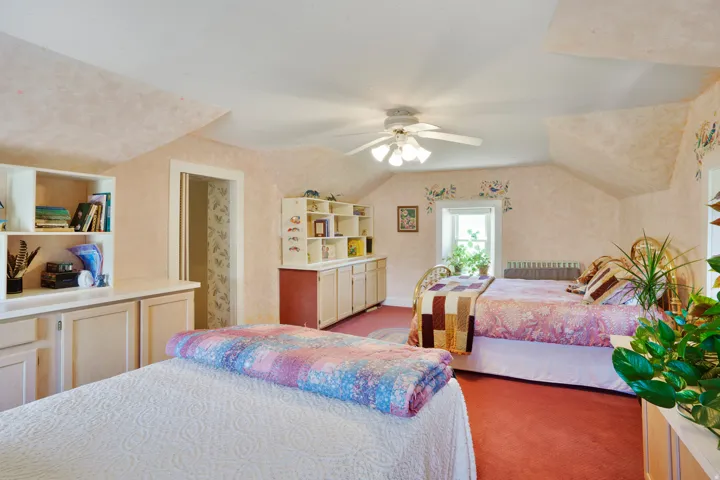 Carpeted room with a sloped ceiling and built-in cabinetry featuring open shelving