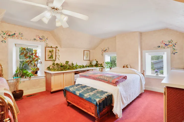 Room featuring sloped ceilings, multiple windows, and a ceiling fan with integrated lighting