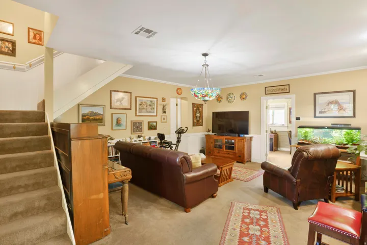 Carpeted living area featuring wainscoting and a staircase with a carpeted runner