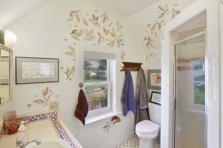 Bathroom featuring a tiled vanity with integrated sink, white window, glass-enclosed shower, and black and white mosaic tile flooring
