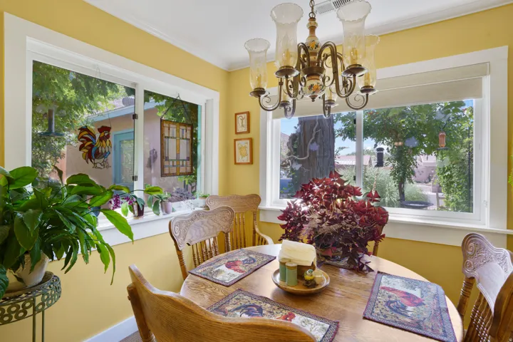 Dining area featuring a wood-finish round table, matching chairs, and a decorative chandelier with glass shades