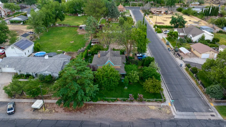 Residential property featuring a tree-lined street frontage, mature landscaping, and a substantial rear yard
