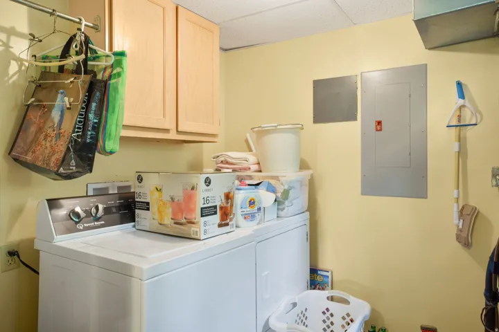 Laundry area featuring a top-load washing machine, built-in cabinetry, and electrical panel access