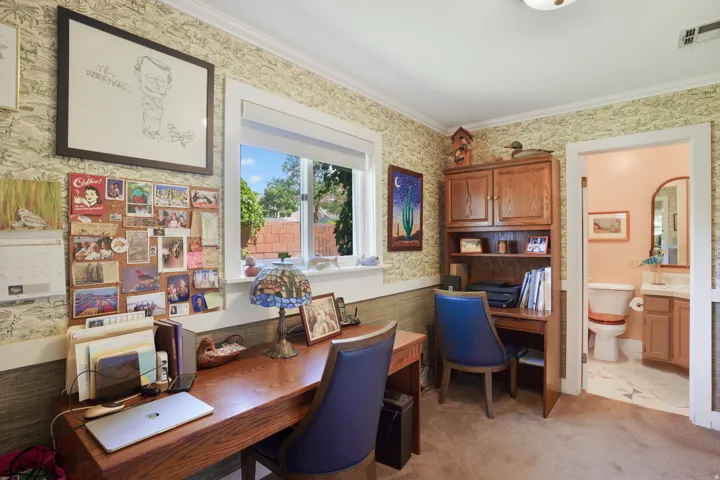 Well-lit interior space featuring a window with exterior views, crown molding, and carpet flooring
