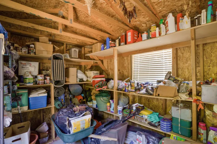 Utility shed interior featuring exposed wood framing, wood-finish panel walls, and a window with horizontal blinds