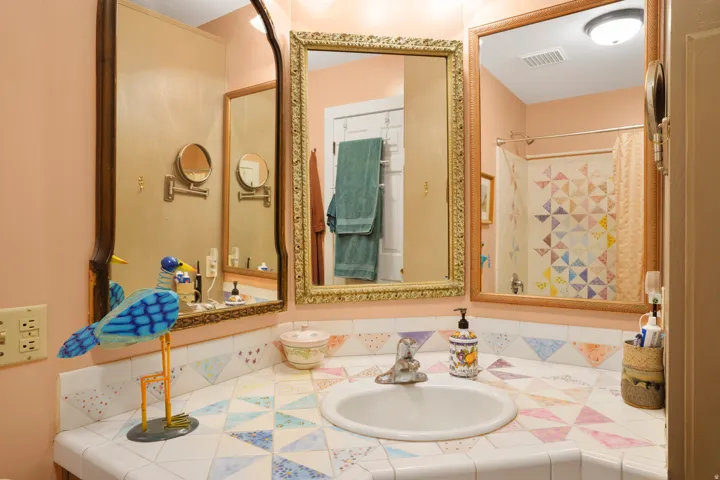Bathroom featuring a tiled countertop with an integrated sink, dual wall-mounted mirrors, and an overhead light fixture