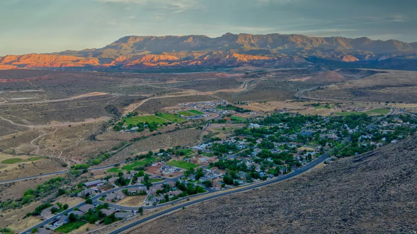 Expansive aerial landscape featuring a residential community, surrounding roads, arid terrain, and distant mountains