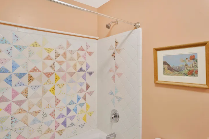 Bathroom featuring a tub and shower combination with custom tiled walls, a brushed nickel showerhead, and a coordinating fixture