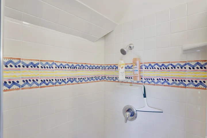 Tiled shower enclosure featuring white subway tiles and a decorative accent band
