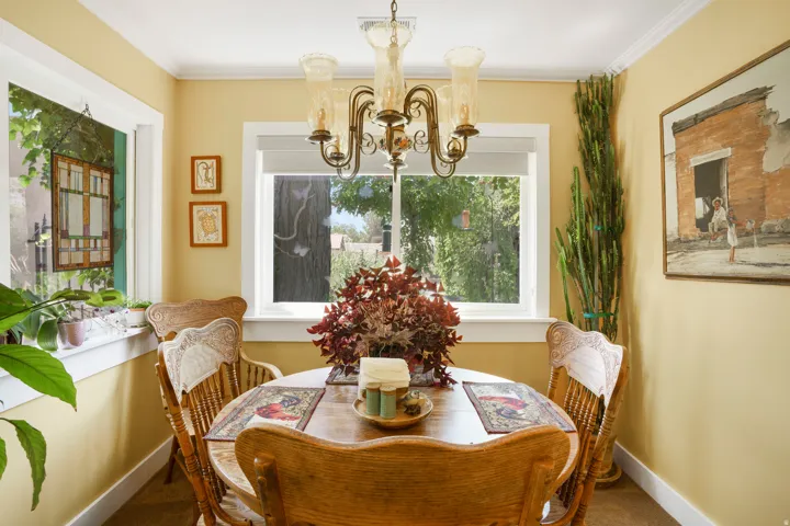 Dining area with light yellow walls, crown molding, and a prominent window