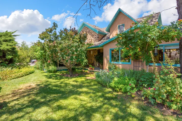 Stucco and stone exterior with teal trim accents, featuring prominent windows and a gabled roofline