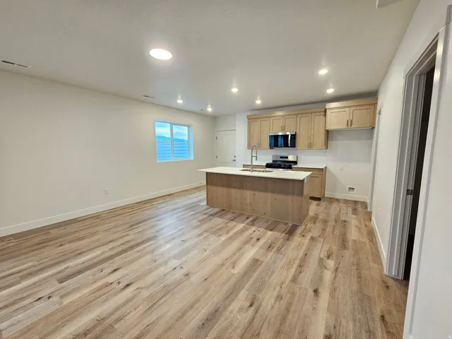 Open concept living area featuring wood-finish flooring, recessed lighting, and a modern kitchen