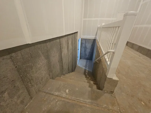 Unfinished basement featuring concrete stairs and foundation walls