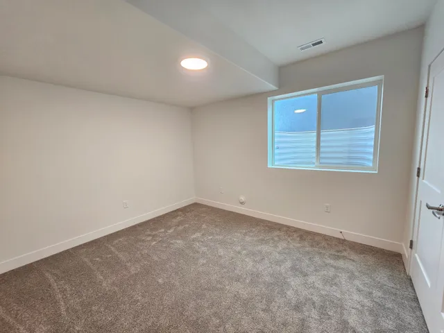 Recessed lighting, light-colored walls, window with frosted glass, white trim, and gray carpet flooring