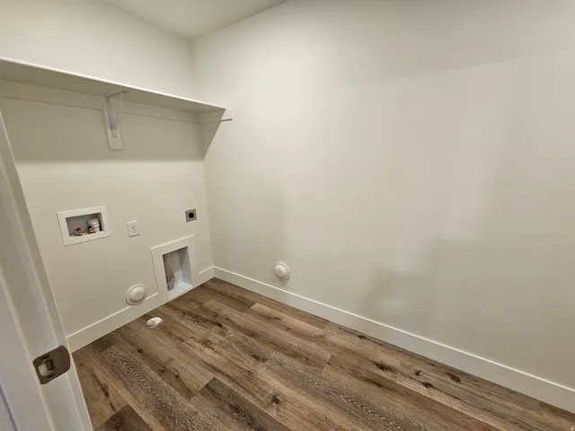 Utility area featuring wood-finish flooring, white walls, and an integrated shelf