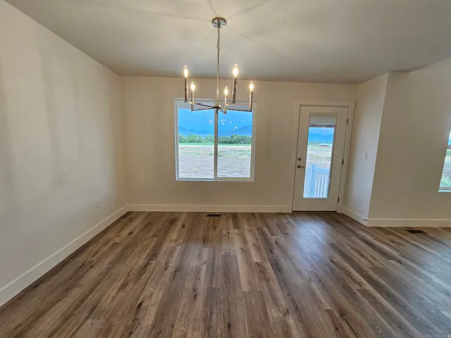 Wood-finish flooring, recessed window, chandelier, white trim, and a glass-paneled exterior door