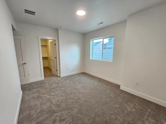 Neutral-toned carpeting, white walls, and a recessed ceiling light