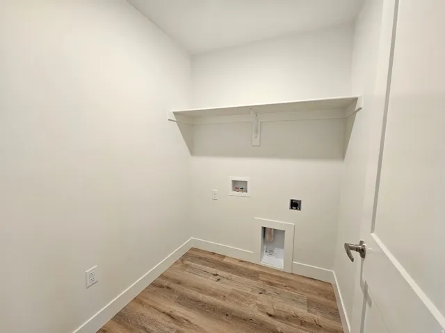 Utility area with wood-finish flooring, a wall-mounted shelf, and integrated hookups