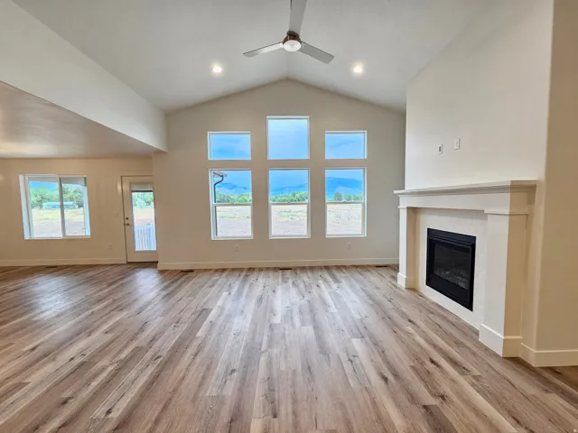 Vaulted ceilings, wood-finish flooring, recessed lighting, and a contemporary fireplace with a white mantel