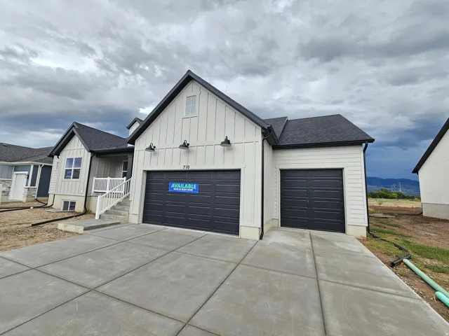 Contemporary exterior with vertical and horizontal siding, dark asphalt shingles, multiple garage doors, and concrete driveway
