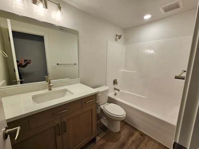 Bathroom featuring a single vanity with stone-finish countertop, undermount sink, and wood-finish cabinetry
