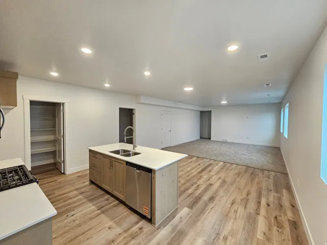 Recessed lighting illuminating the kitchen island with an undermount dual-basin sink and stainless steel dishwasher