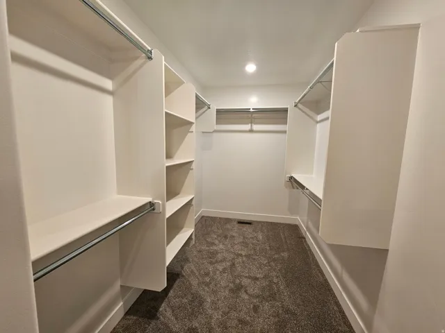 Walk-in closet featuring built-in shelving, hanging rods, and recessed lighting