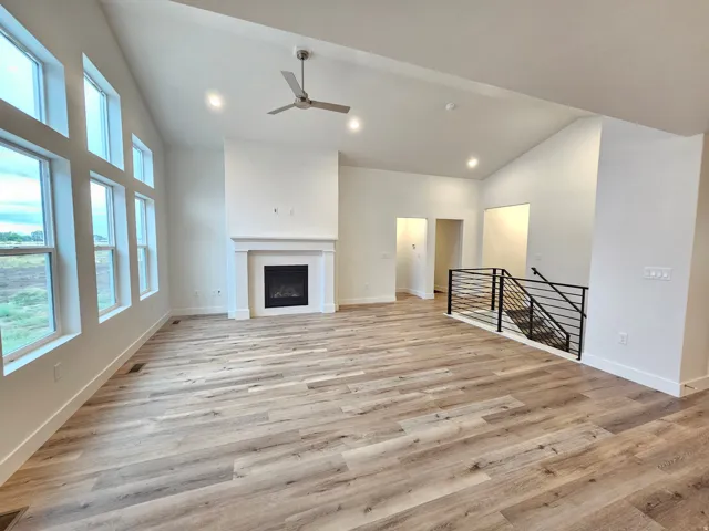 Vaulted ceiling, recessed lighting, wood-finish flooring, fireplace with mantel, and black metal staircase railing