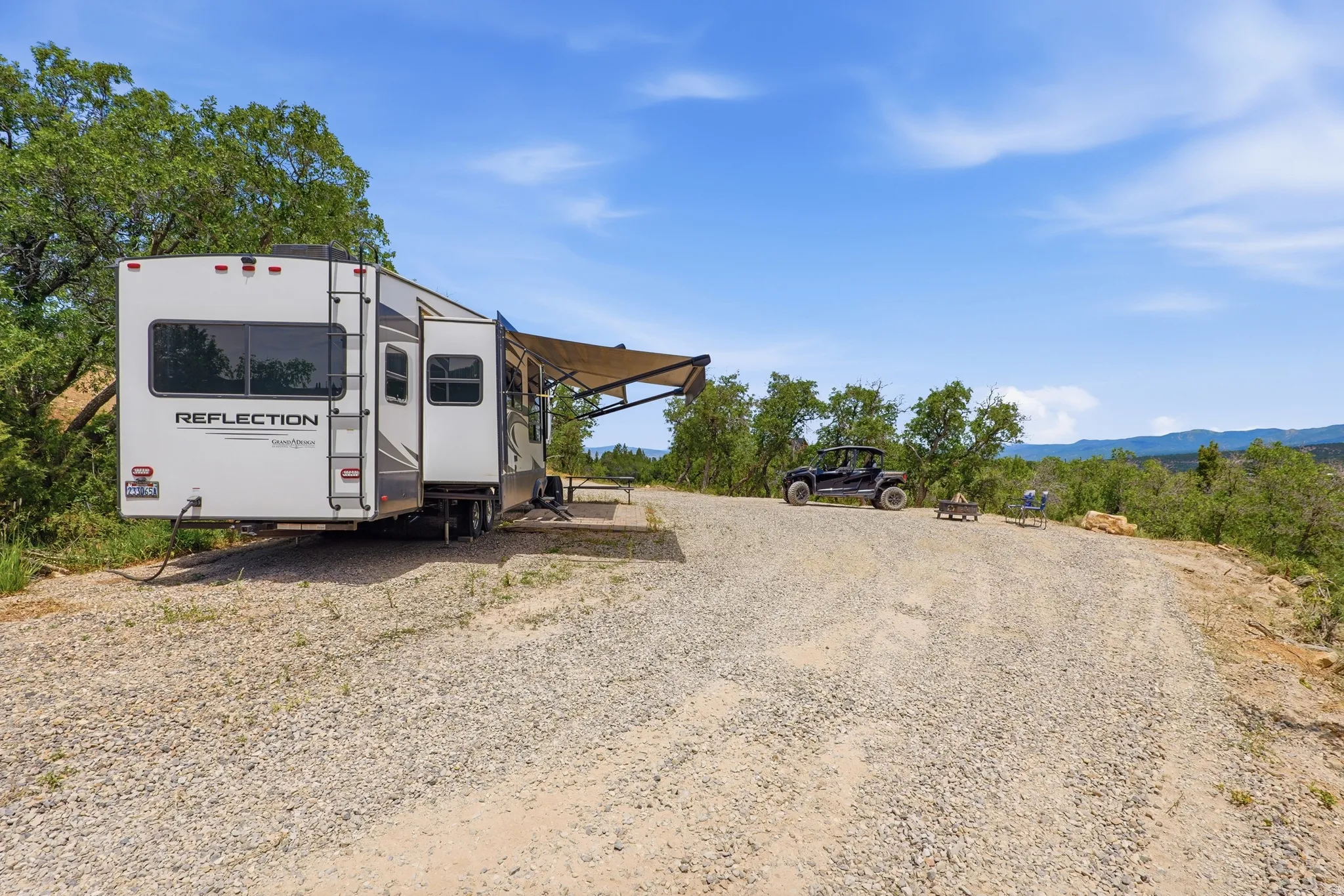 Gravel-surfaced lot with natural tree surroundings and an expansive mountain backdrop