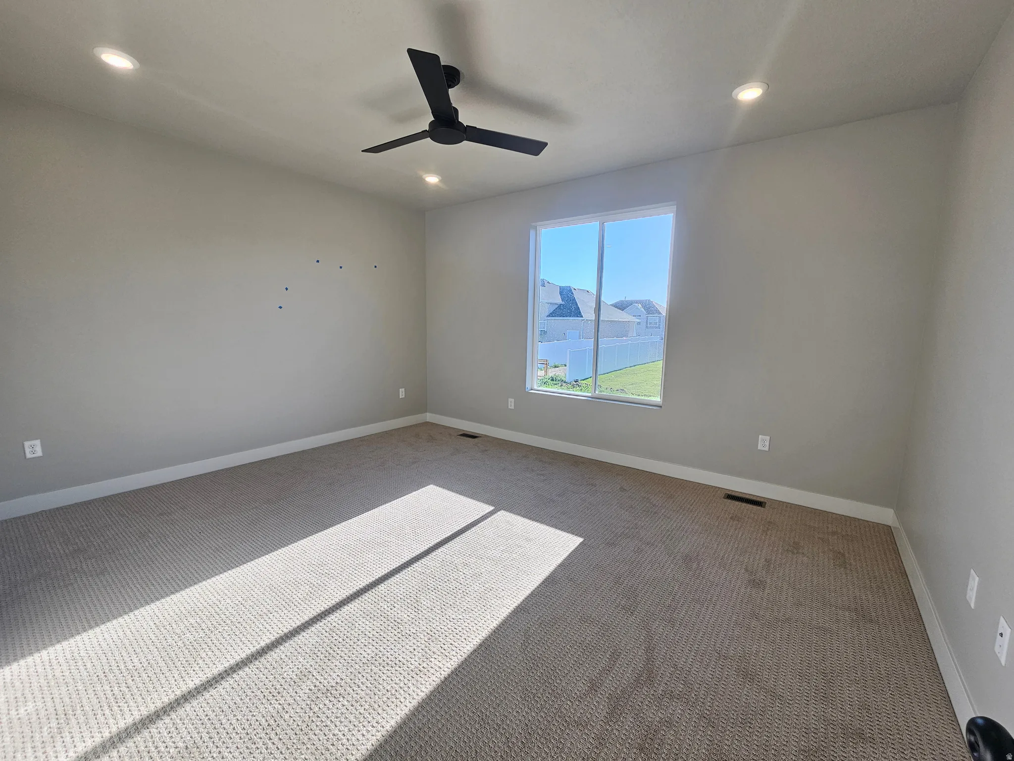 Carpeted room with a large window, a black ceiling fan, and recessed lighting