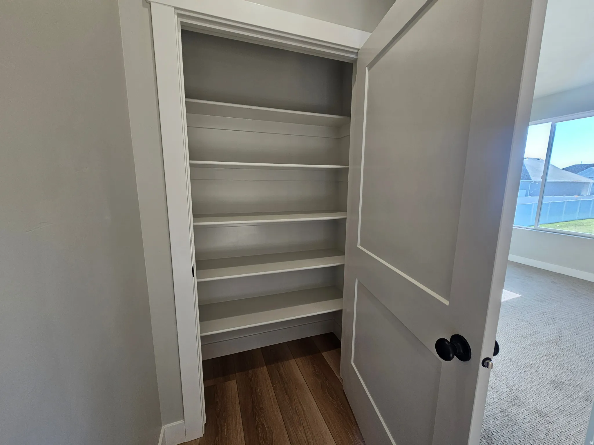 Built-in shelving unit with multiple rows for storage, framed by white trim and a neutral-toned door with black hardware