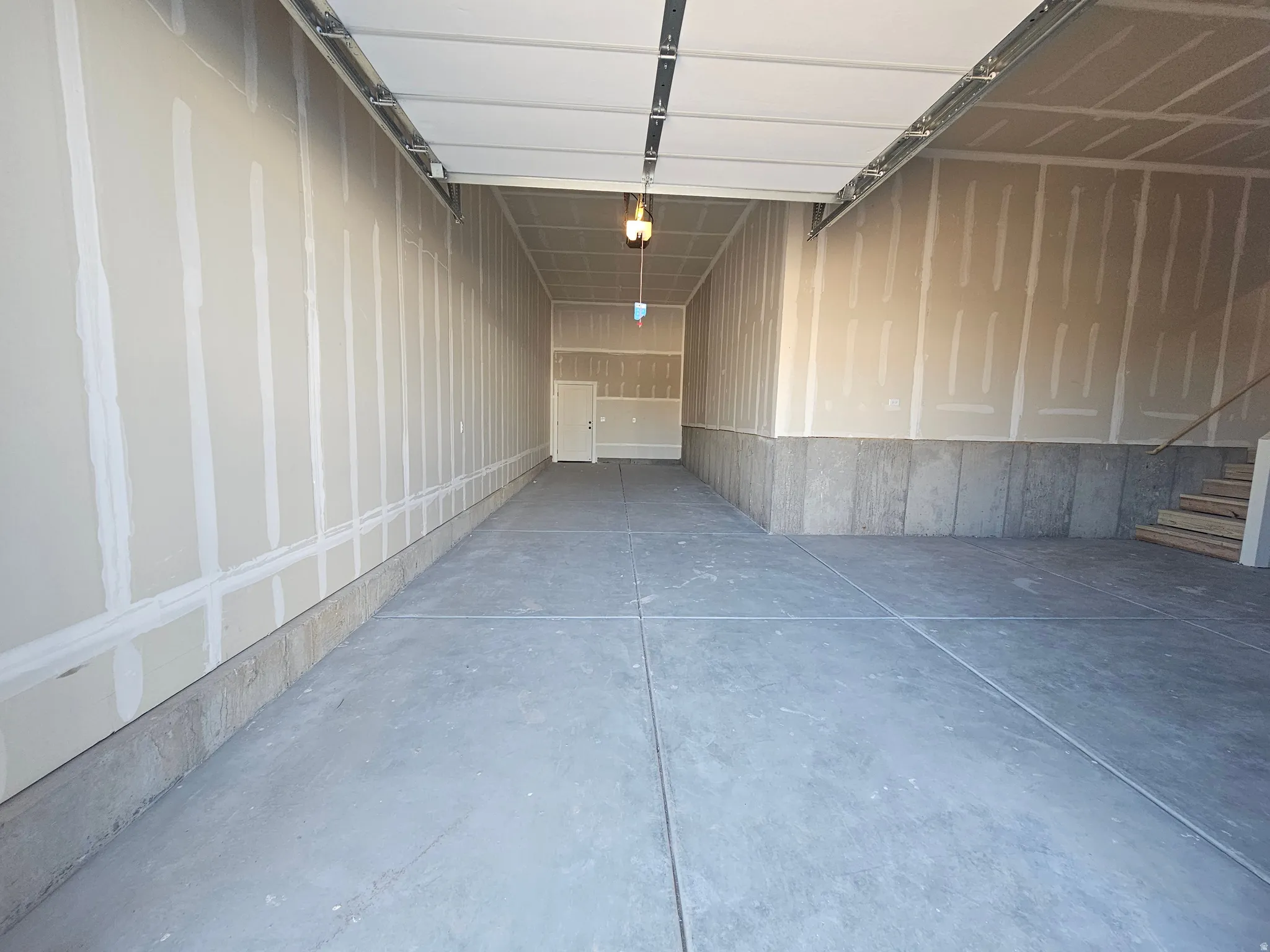 Spacious two-car garage featuring a concrete floor, unfinished drywall, and a raised ceiling