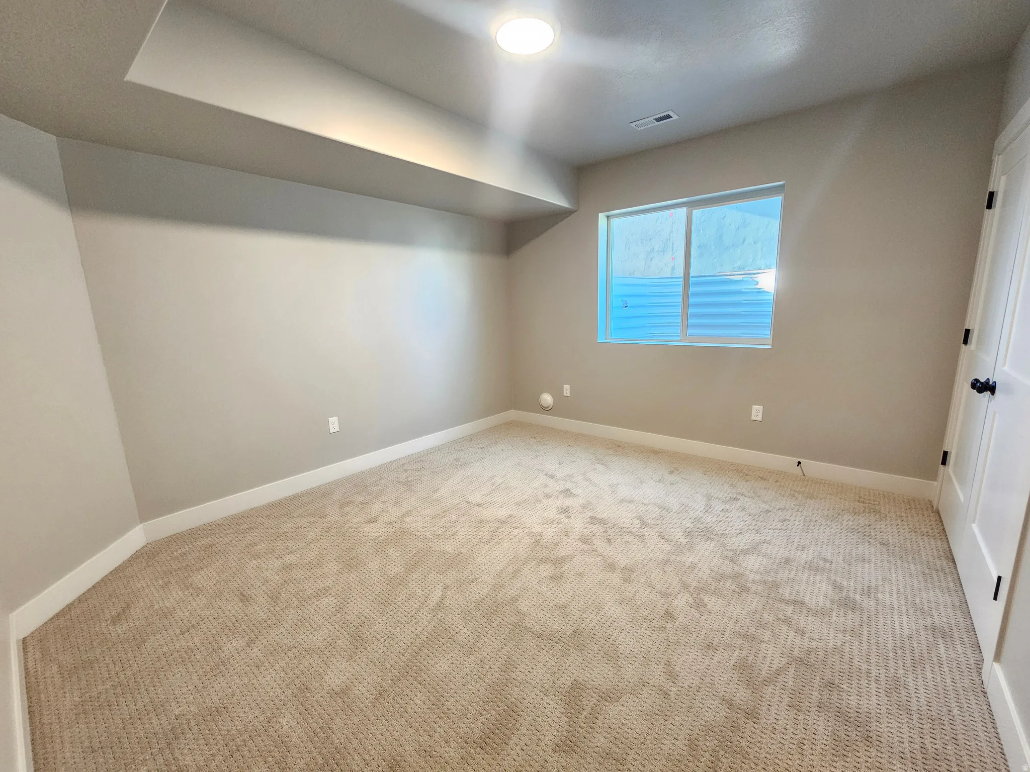 Carpeted room with neutral wall tones and a window
