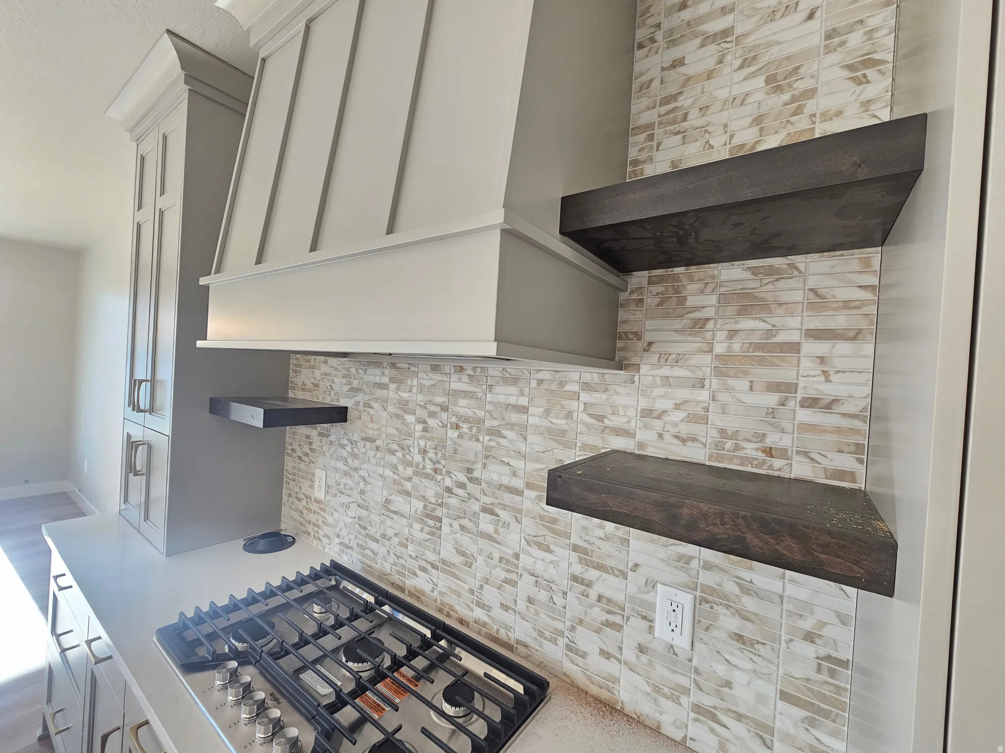 Kitchen featuring a built-in gas range, a decorative range hood, and a tile backsplash