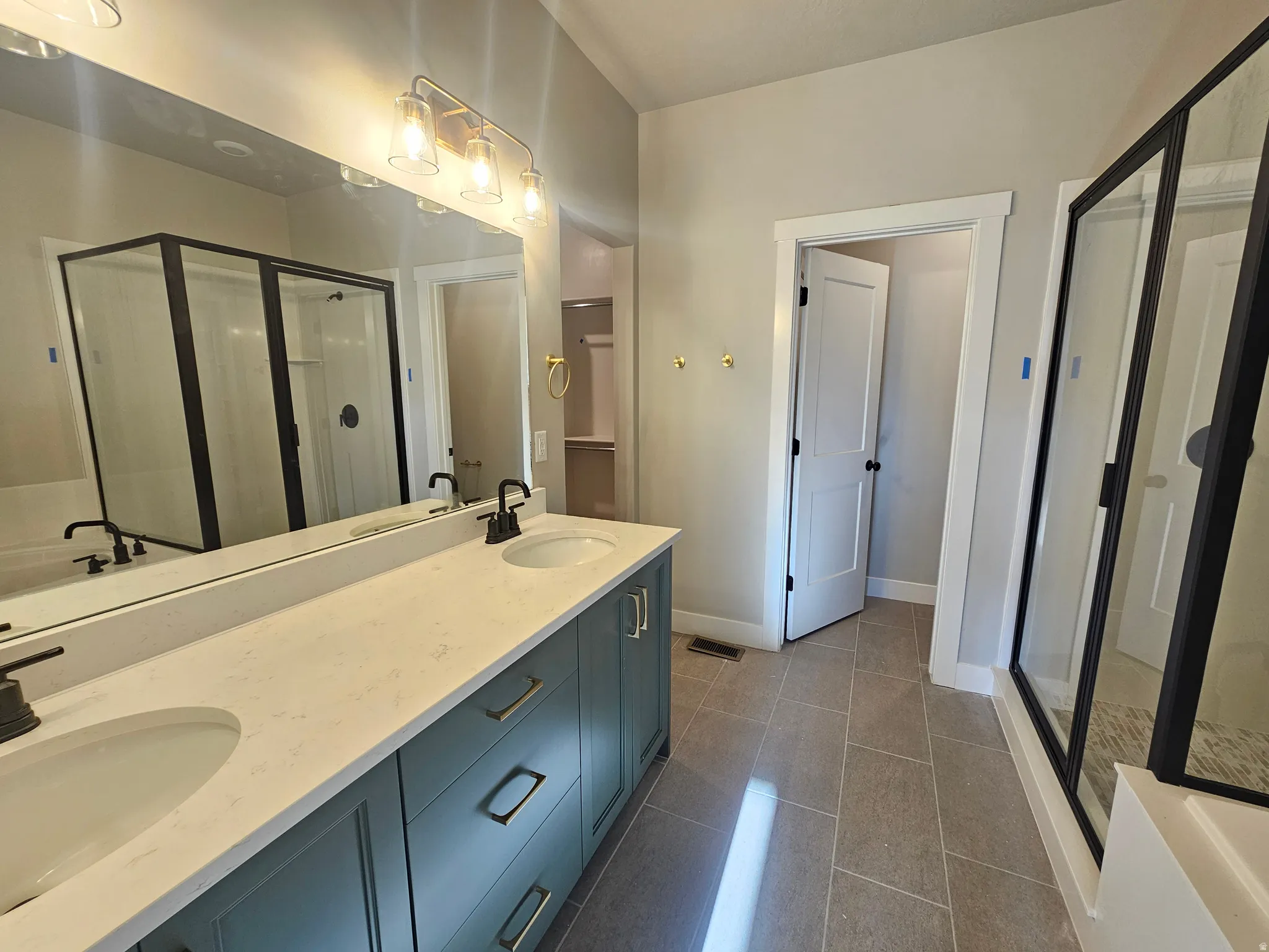 Dual vanity with quartz countertop, matte black fixtures, and integrated sinks