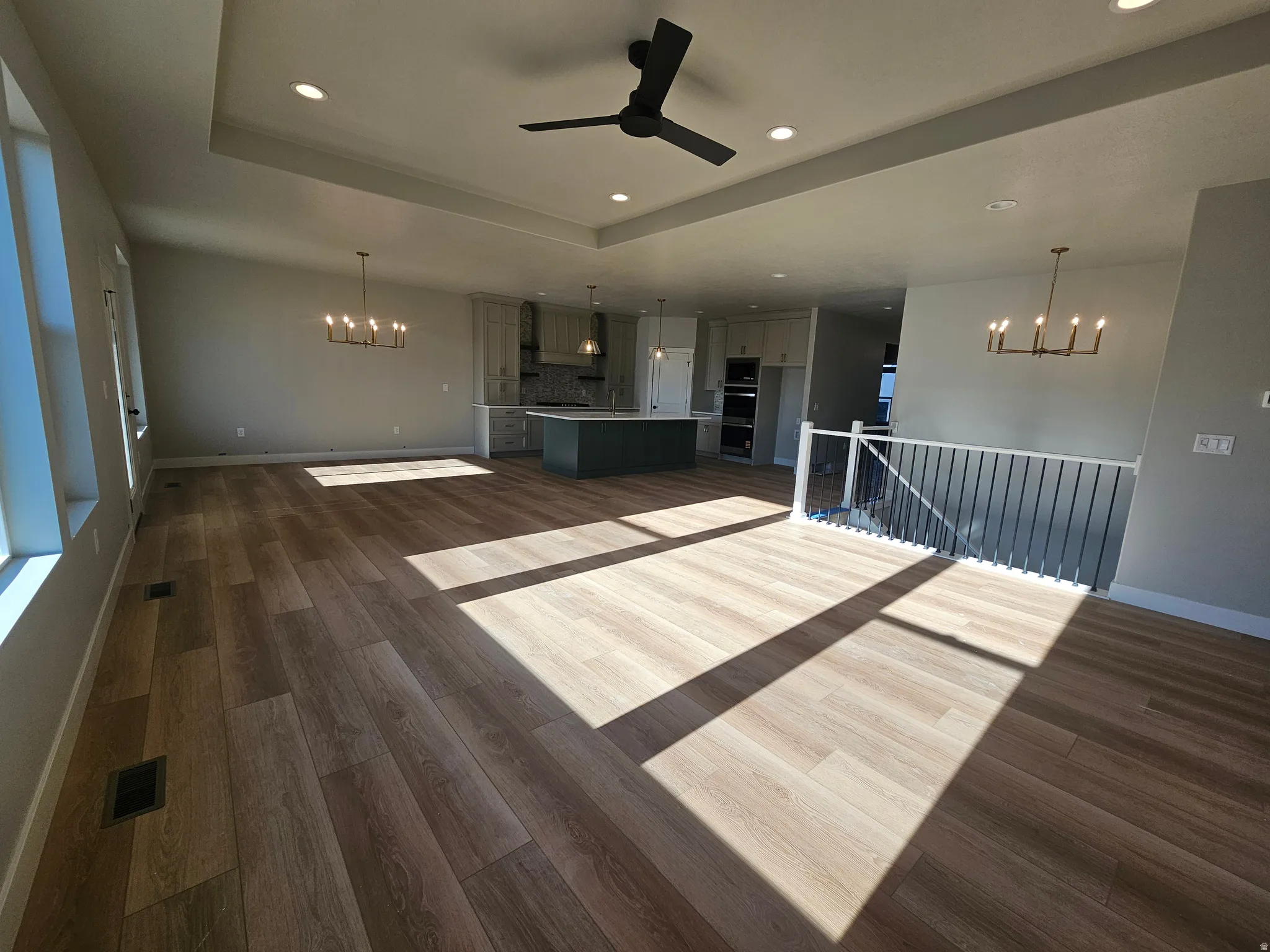 Spacious open-concept interior featuring wood-finish flooring, a contemporary black ceiling fan, and recessed lighting