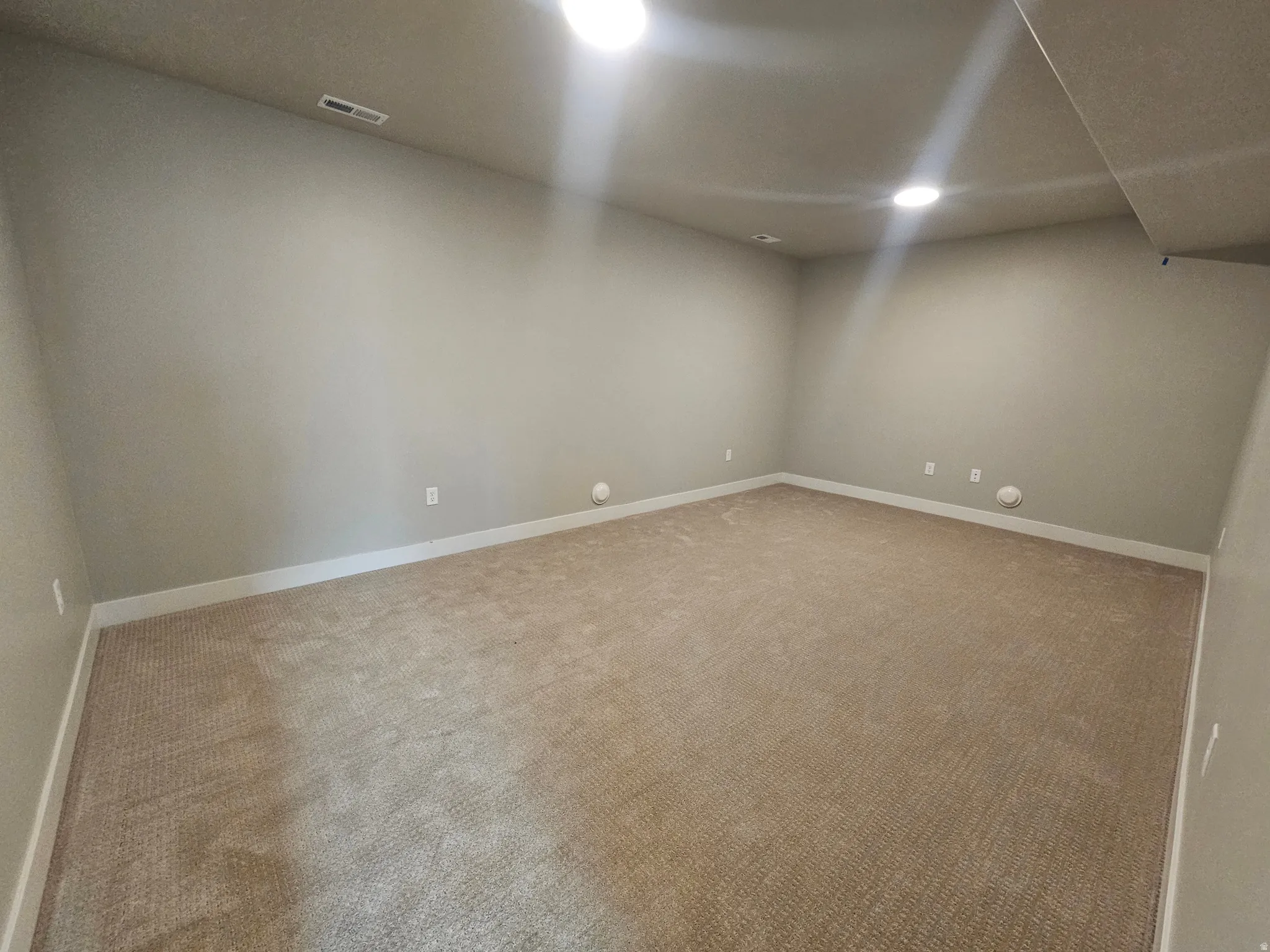 Spacious interior room featuring neutral wall paint, recessed lighting, baseboard trim, and light brown carpeting