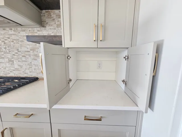 Light gray shaker-style cabinetry with gold-finish hardware, quartz countertops, and a subway tile backsplash