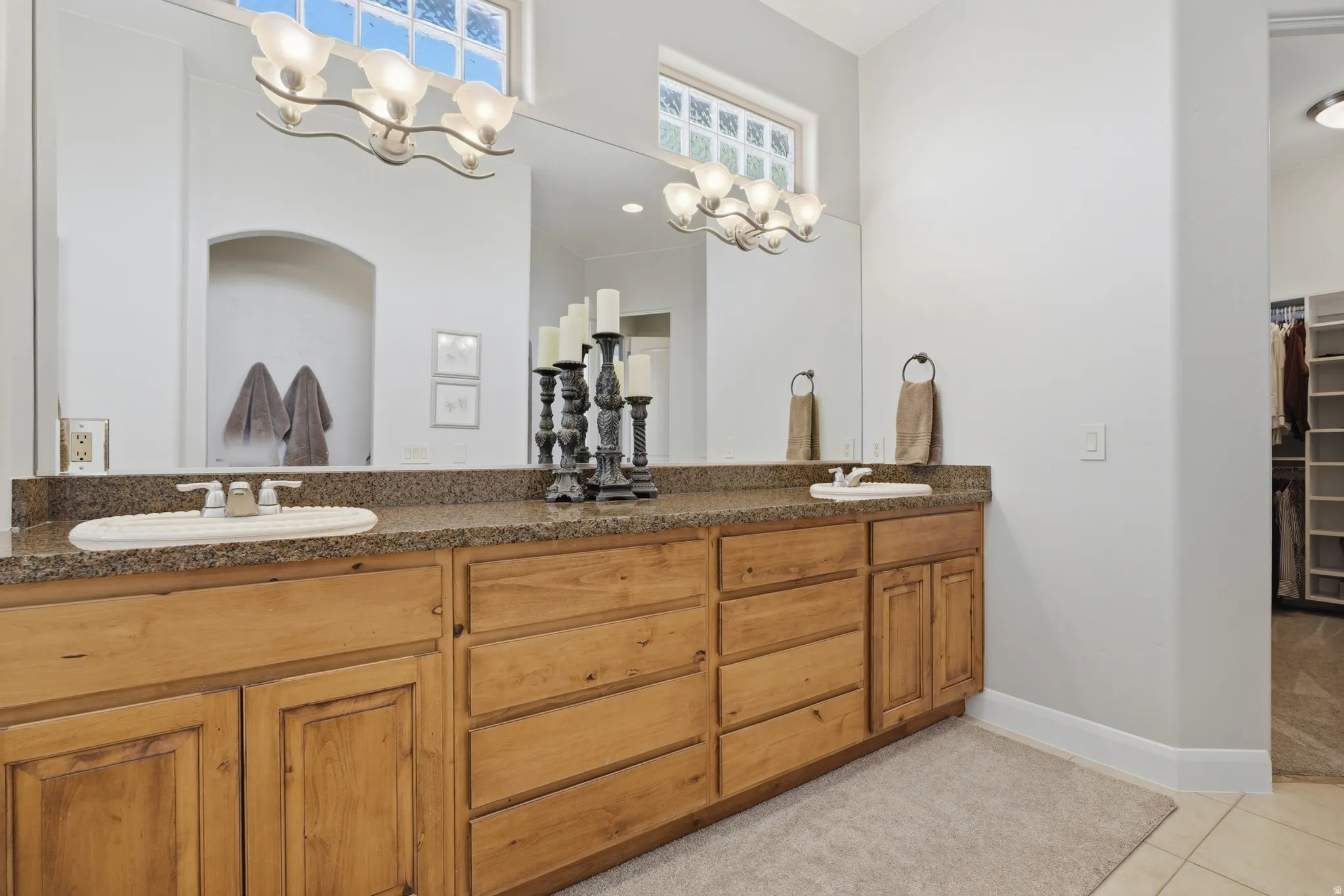 Dual vanity with integrated sinks, granite countertop, light wood cabinetry, and a full-width mirror
