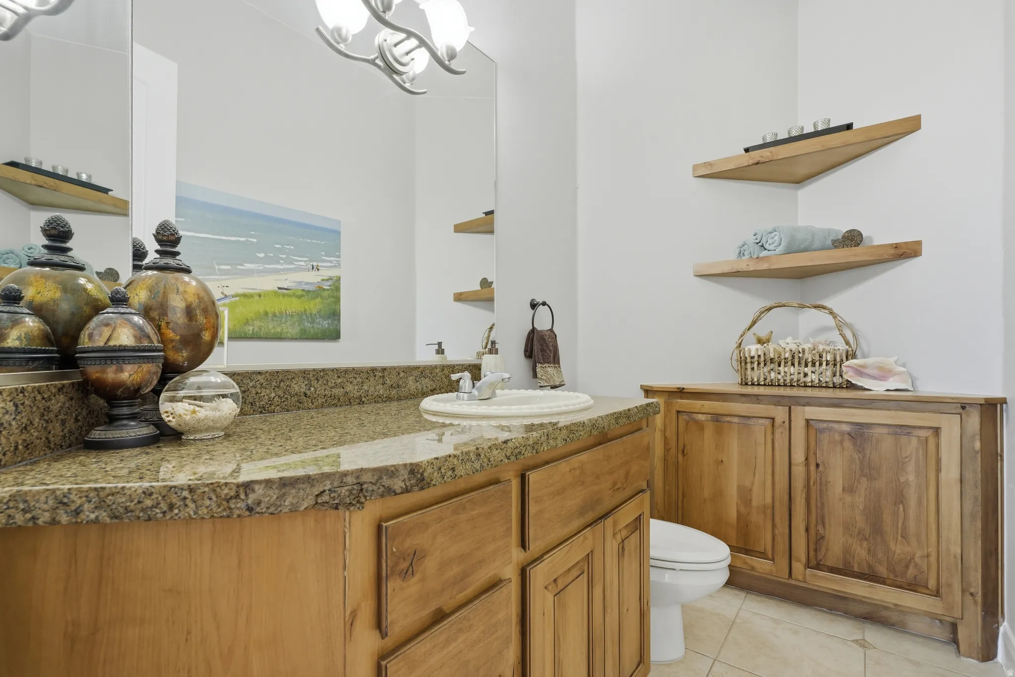 Bathroom featuring a light-toned vanity with a stone-finish countertop, an undermount sink, and a large wall-mounted mirror