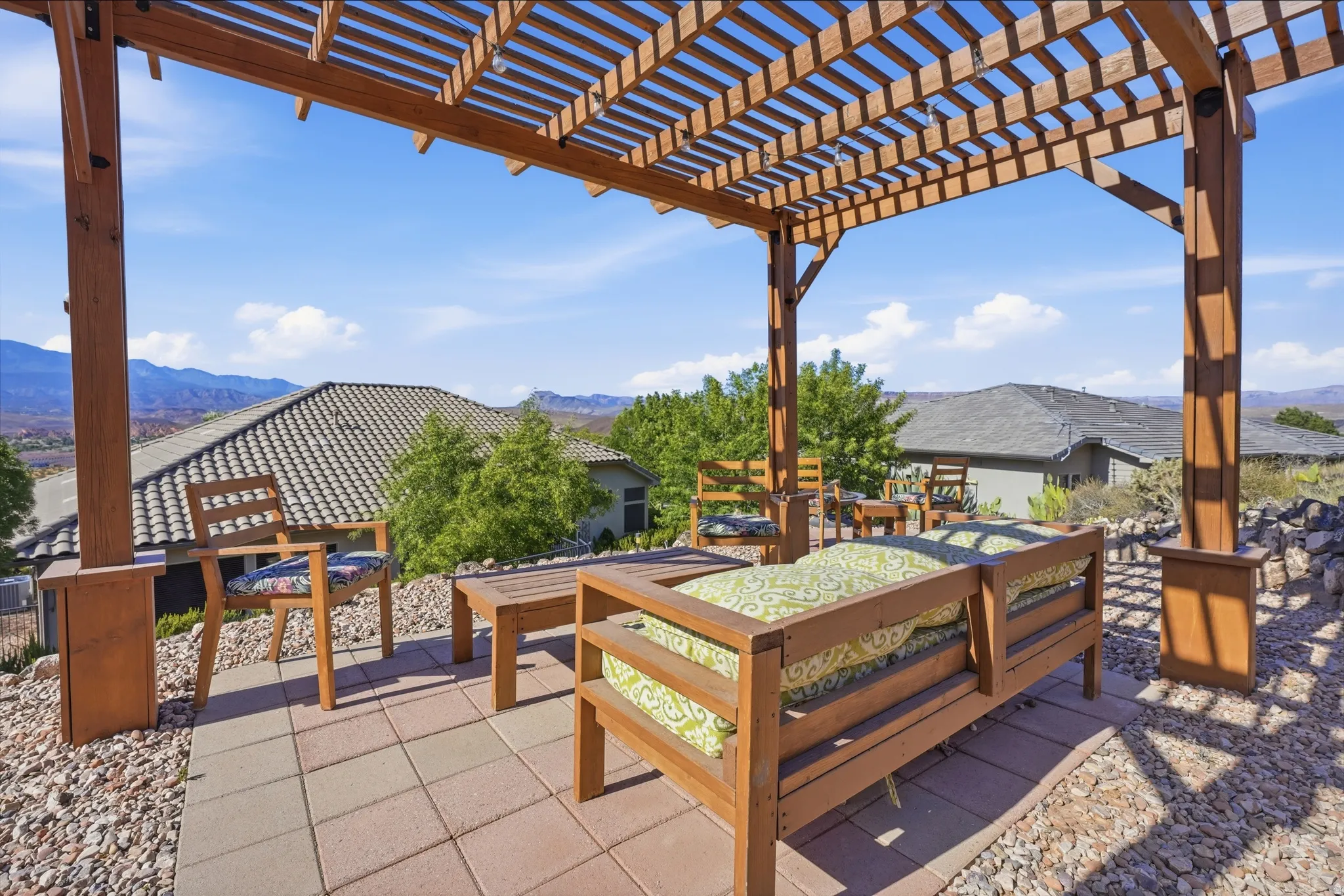 Outdoor pergola-covered patio featuring paver stones and decorative gravel