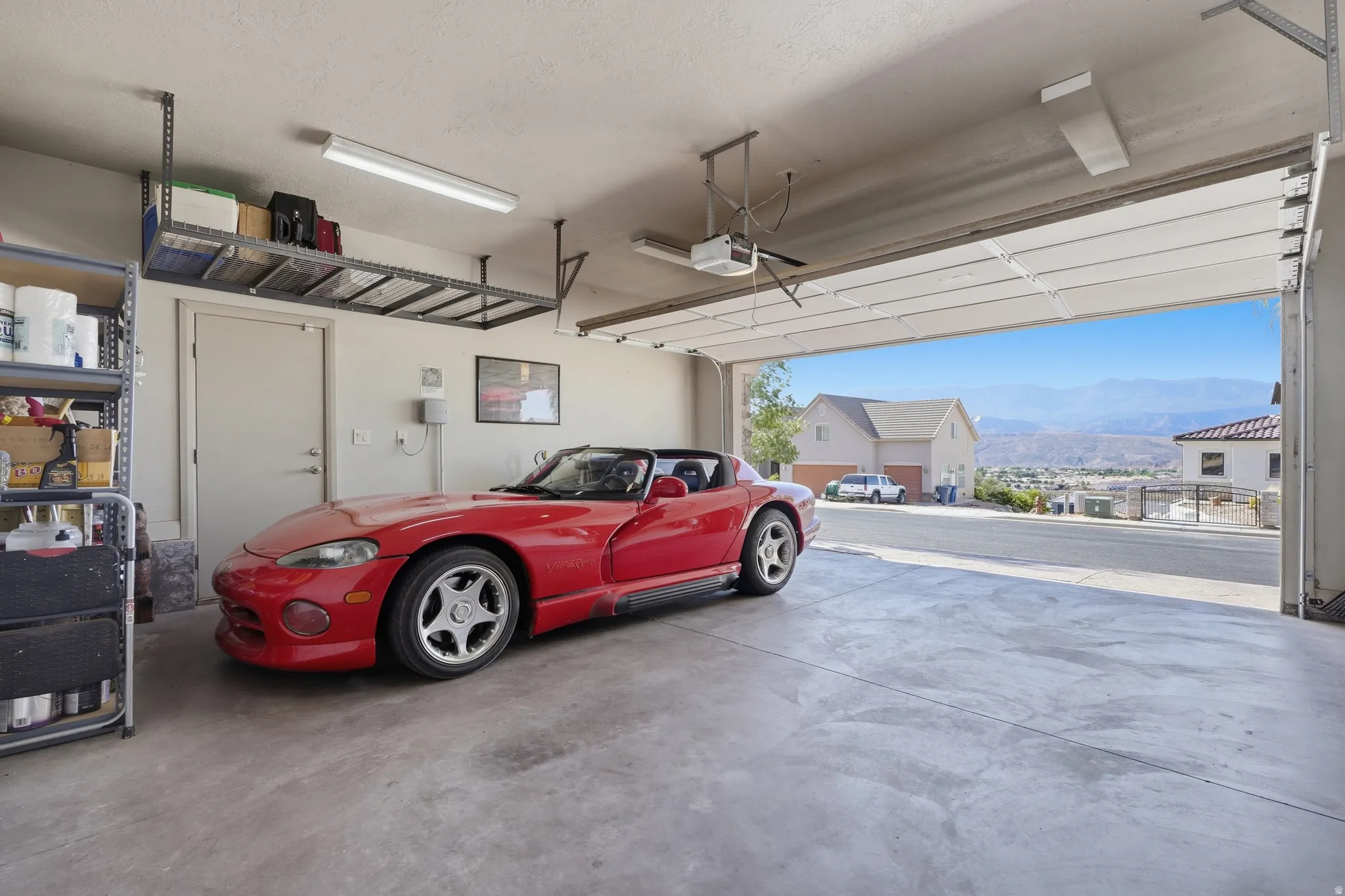 Spacious garage featuring a concrete floor, overhead storage racks, fluorescent lighting, and an automatic garage door opener