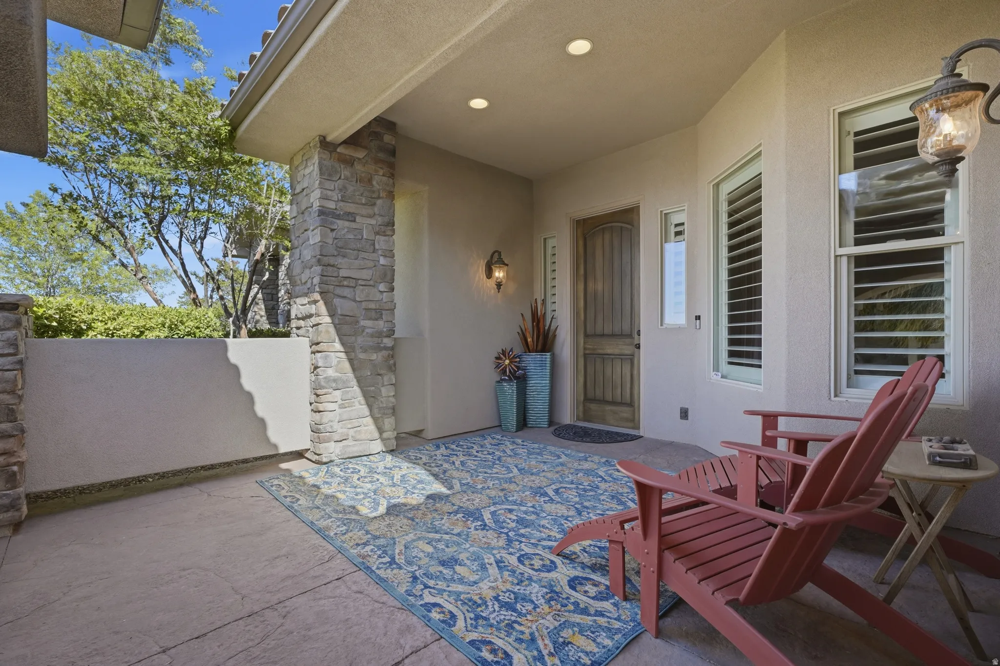Stucco exterior with stone veneer accents, an arched wood entry door, and shuttered windows