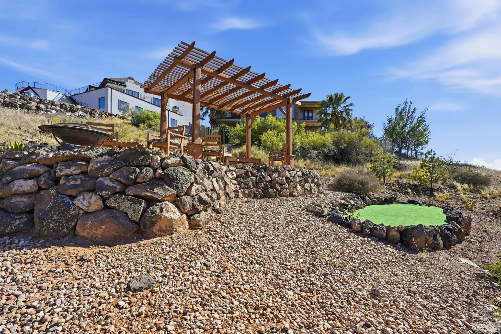 Outdoor entertaining area featuring a wood pergola and a stone-lined putting green